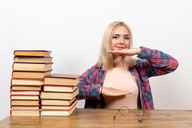 Studentin sitzt gerade mit Büchern, die Größe auf Weiß zeigen