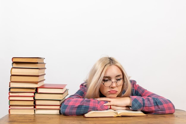 Studentin sitzt mit Büchern, die sich auf Weiß müde fühlen