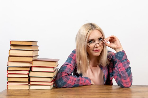 Studentin sitzt mit verschiedenen Büchern auf hellweiß