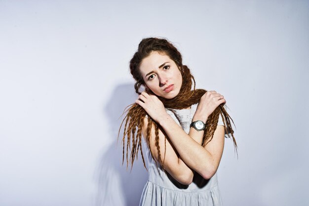 Studio-Shooting von Mädchen in grauem Kleid mit Dreads-Zöpfen auf weißem Hintergrund