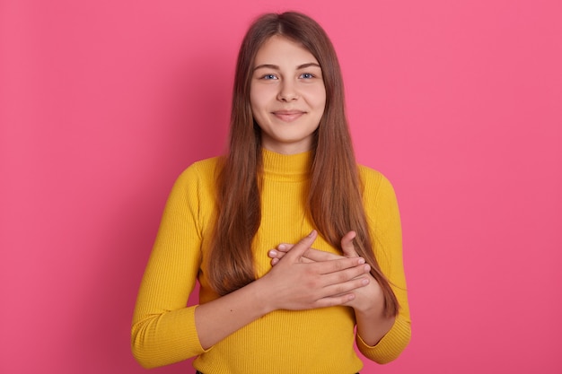 Studioaufnahme der jungen kaukasischen Dame, die Innen gegen Rosa aufwirft.