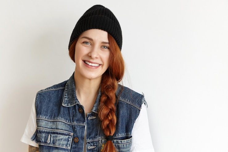Kostenlose Foto studioaufnahme der stilvollen jungen rothaarigen frau, die ärmellose jeansjacke über weißem t-shirt trägt