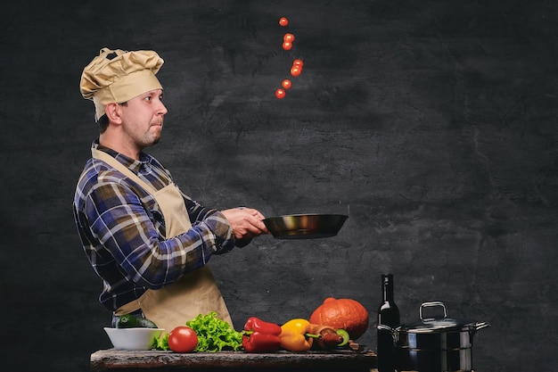 Studiobild eines männlichen Chefkochs, der Mahlzeiten auf einer Pfanne zubereitet.