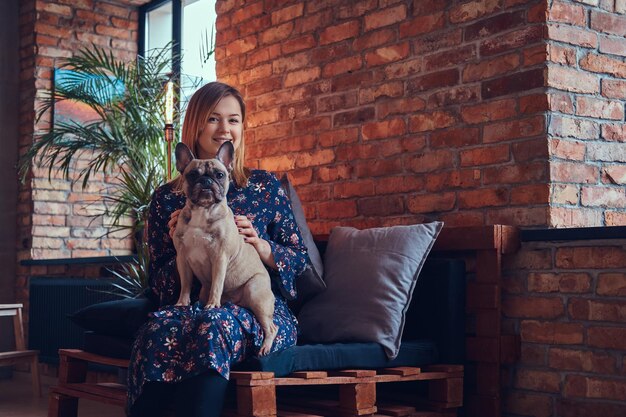 Studioporträt einer attraktiven, fröhlichen Blondine in einem Raum mit Loft-Interieur.