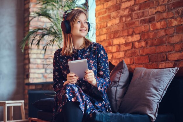 Studioporträt einer attraktiven, fröhlichen Blondine in einem Raum mit Loft-Interieur.