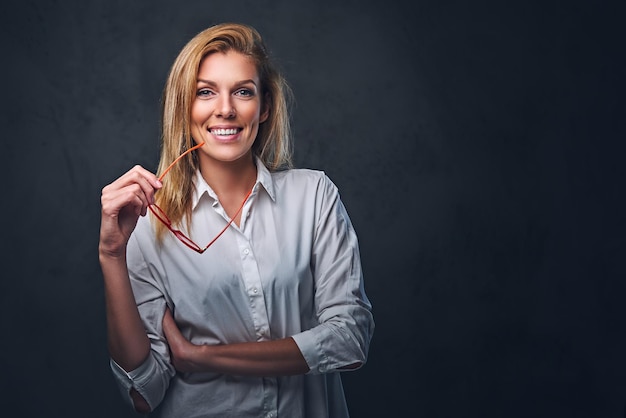 Studioporträt einer blonden Frau in einem weißen Hemd und einer roten Brille.