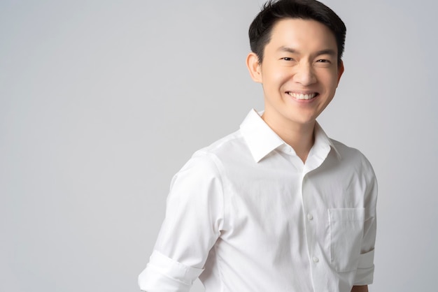 Studioporträt eines halben Körpers eines attraktiven jungen asiatischen Geschäftsmannes mit weißem Hemd isoliert auf grauem Hintergrund