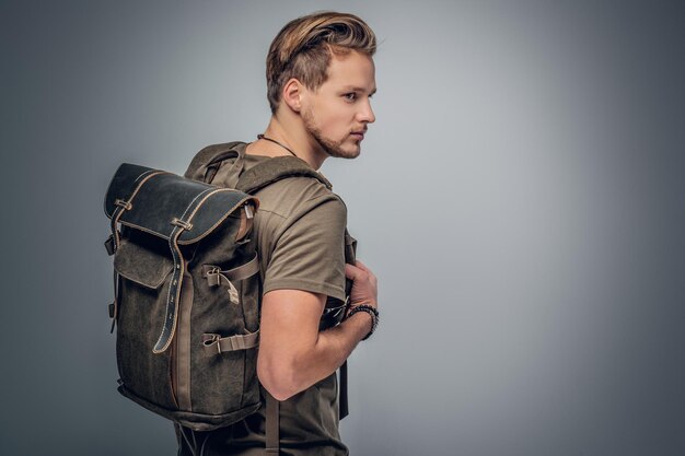 Studioporträt von Rucksacktouristen im urbanen Stil mit Tätowierung auf den Armen auf grauem Vignettenhintergrund.