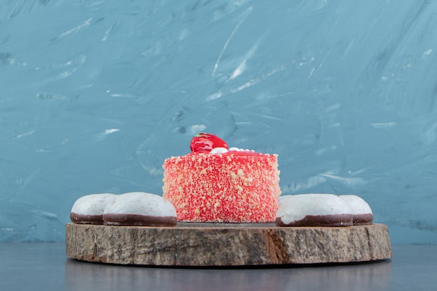 Stück Erdbeerkuchen und Kekse auf Holzstück.