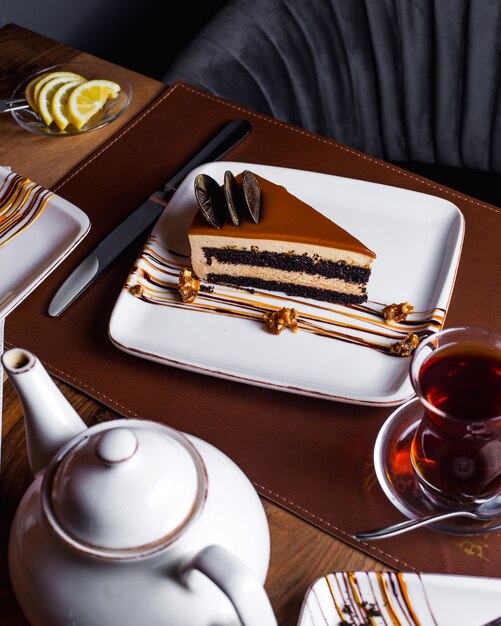 Stück Karamellkuchen mit Schokoladenkeksen verziert mit Tee serviert
