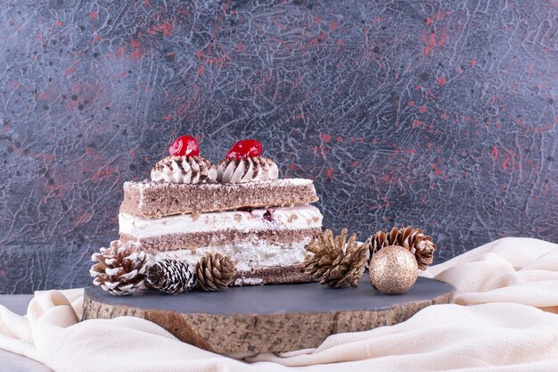 Stück Kuchen mit Weihnachtsschmuck auf Holzstück. Foto in hoher Qualität
