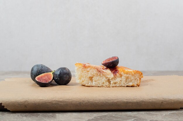 Stück Kuchen und frische Feigen auf Holzbrett.