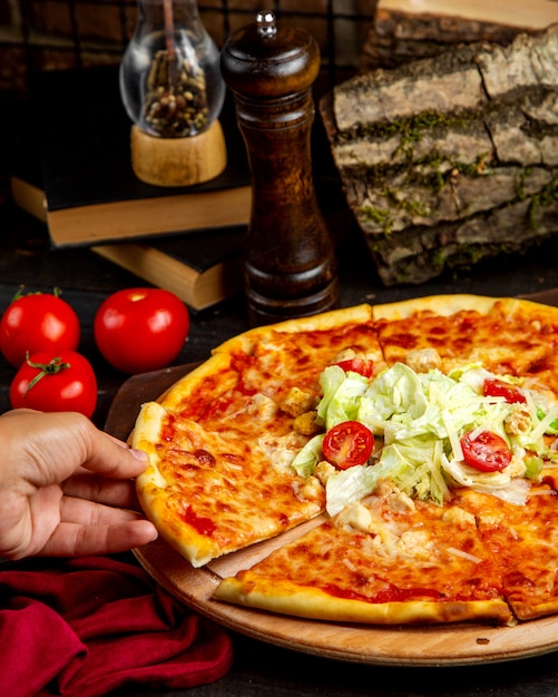 Stück Pizza mit Huhn und Tomate auf einem Holzbrett