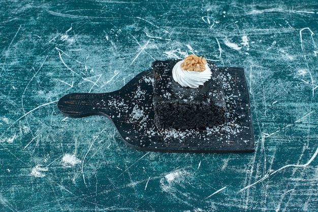 Kostenloses Foto stück schokoladenkuchen auf einem kleinen brett auf blau.