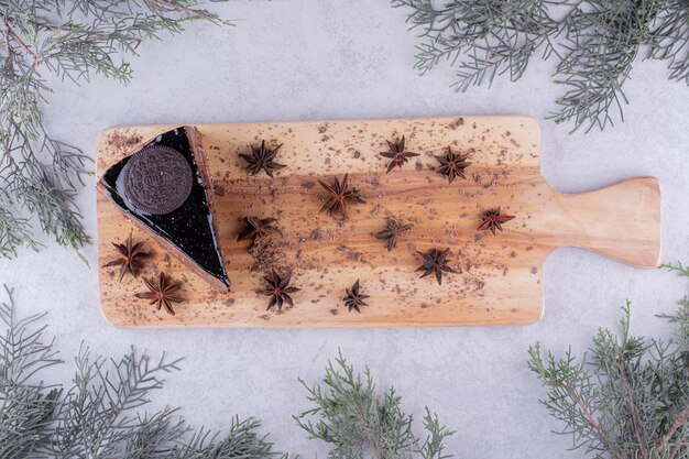 Stück Schokoladenkuchen mit Nelken auf Holzbrett. Foto in hoher Qualität