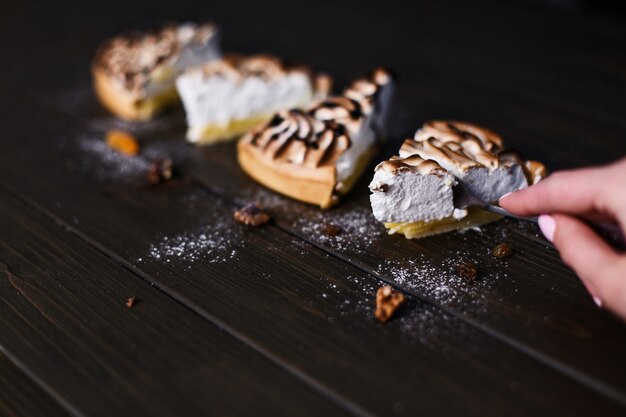 Stück Zitronenkäsekuchen mit weißer Creme diente auf einem dunklen Holztisch