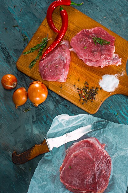 Stücke rohes Schweinesteak mit Gewürzen und Kräutern Rosmarin