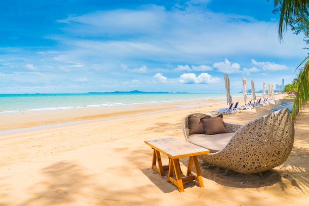 Stuhl und Tabelle, die auf dem Strand und dem Meer mit blauem Himmel speisen