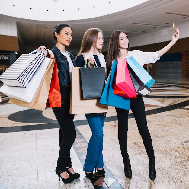 Stylische Mädchen nehmen Selfie mit Taschen