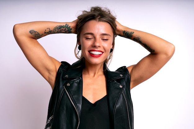 Stylische positive Frau mit tattos schwarzem Schaum und hellen Lippen glücklich emotionalem Gesicht weißem Hintergrund
