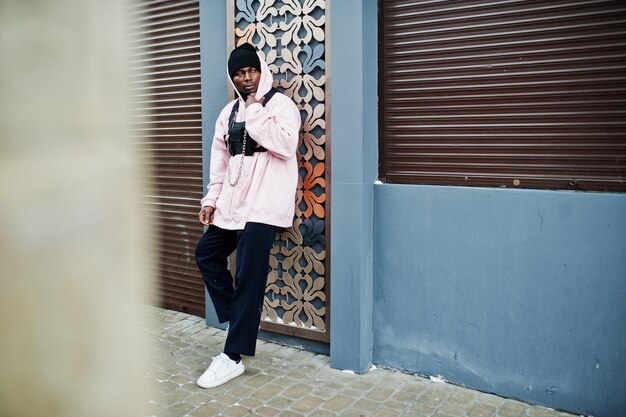 Stylischer afroamerikanischer Mann im urbanen Stil in rosafarbenem Hoodie posierte Afro-Rapper-Typ