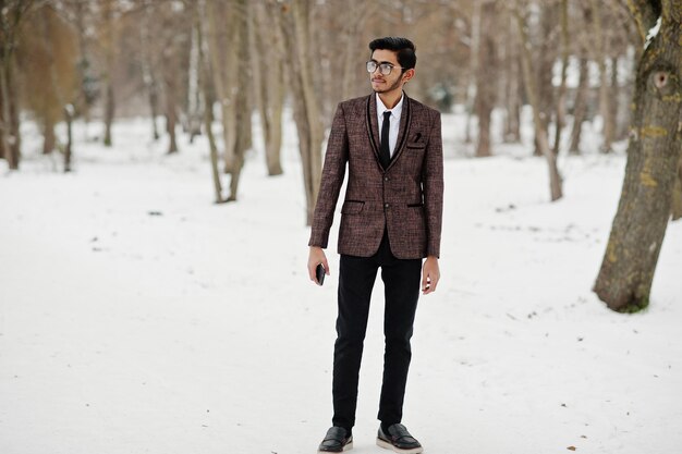 Stylischer indischer Student in braunem Anzug und Brille posierte am Wintertag im Freien