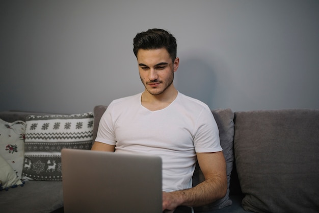 Suchender Laptop der jungen Frau auf Sofa