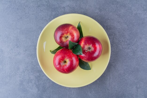 Süße Äpfel und Blatt auf Teller auf Marmortisch.