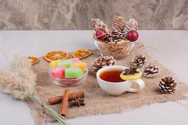 Süße Bonbons mit leckerer Tasse Tee auf Sackleinen. Hochwertiges Foto