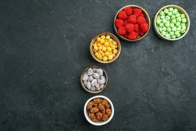 Süße Bonbons von oben mit Konfitüren auf dunkler Oberfläche Süßigkeiten süßer Nuss-Goodie-Tee