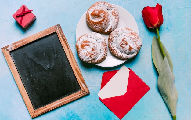 Süße Brötchen auf Platte mit leerer Tafel