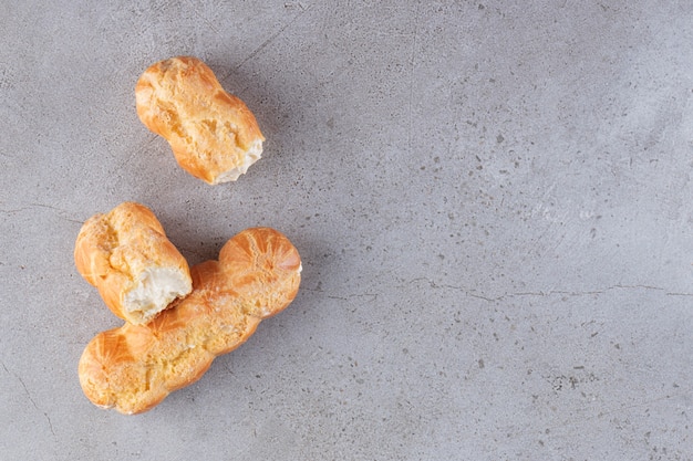 Süße Eclairs gefüllt mit Schlagsahne auf Marmoroberfläche