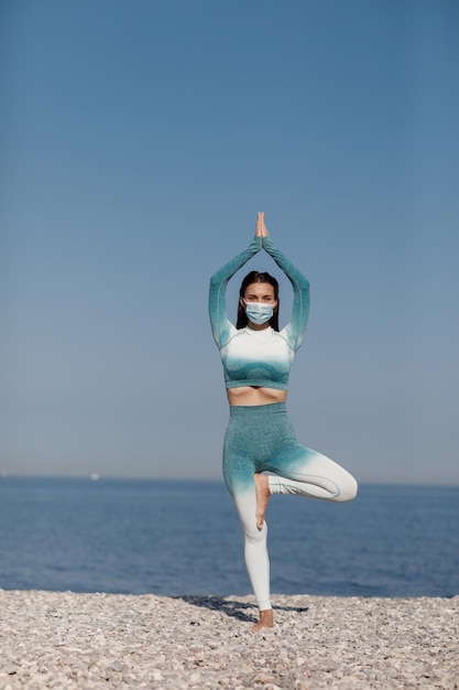 süße Frau, die Yoga am Strand in der Nähe des Meeres macht