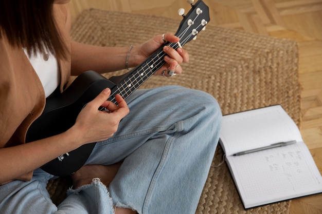 Süße Frau, die zu Hause Ukulele spielt