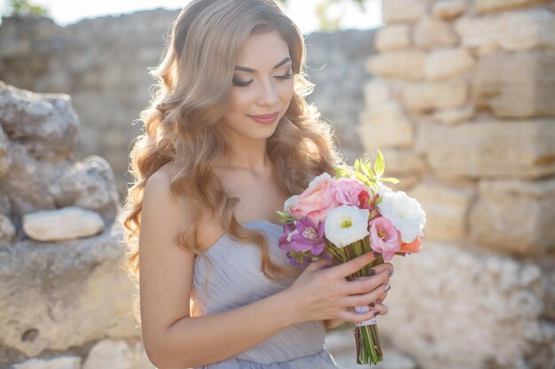 süße junge Frau im Kleid mit Blumen im Freien