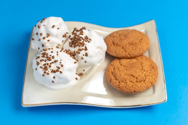 Süße Kekse der Vorderansicht mit köstlicher Eiscreme-Innenplatte auf dem blauen Schreibtisch