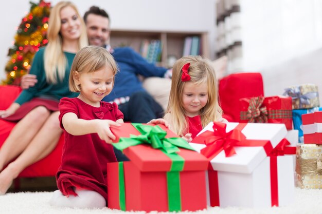 Süße kleine Mädchen, die Weihnachtsgeschenke öffnen