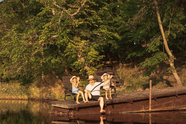 Süße kleine Mädchen und ihr Opa fischen am See oder Fluss