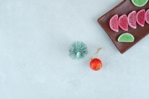 Süße Marmelade mit Weihnachtskugel und Baum auf dunklem Teller.