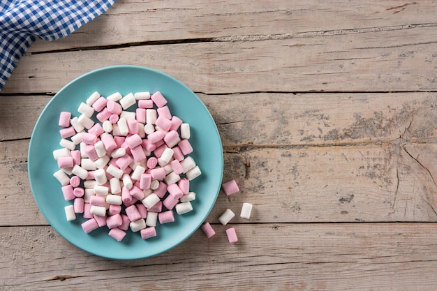 Süße Marshmallows in einem blauen Teller auf Holztisch