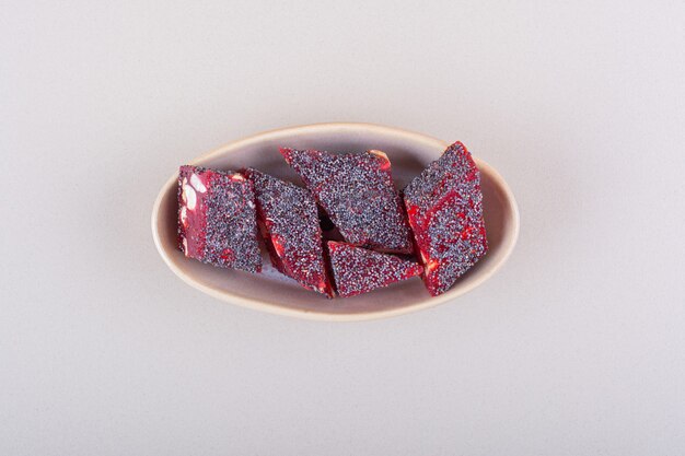 Süße rote Bonbons mit Nüssen in beige Schüssel auf weißem Hintergrund. Foto in hoher Qualität