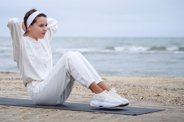 Süße Sportlerin macht Situps auf der Matte am Strand Foto in hoher Qualität