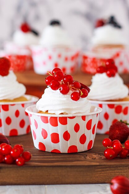 Süße Vanille Cupcakes mit Beerenmarmeladenfüllung und Käsecreme, dekoriert mit Sommerbeeren