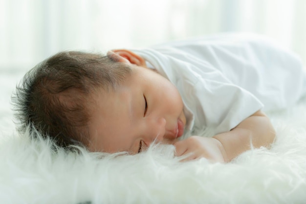 Süßer Babyjunge schläft mit süßem Traum und friedlichem, weißem, weichem Bett