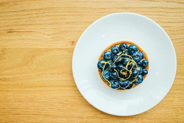 Süßer Dessert mit Blaubeertörtchen in weissem Teller