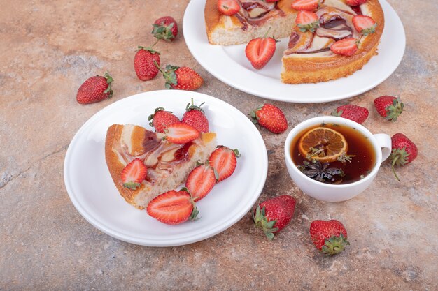 Süßer Kuchen mit Erdbeere in einem weißen Teller mit einer Tasse Tee