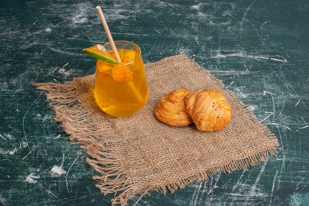 Süßer Saft mit leckerer Bäckerei auf Marmoroberfläche.