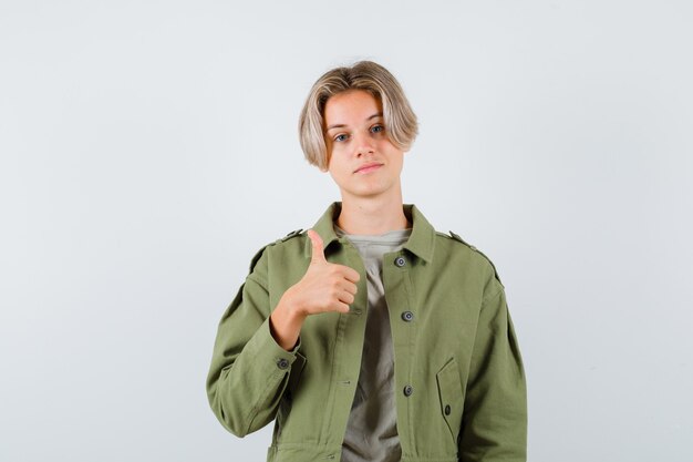Süßer Teenager in grüner Jacke, der Daumen nach oben zeigt und selbstbewusst aussieht, Vorderansicht.