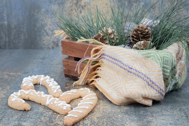 Kostenloses Foto süßer weihnachtsplätzchen mit tannenzapfen im korb auf marmortisch