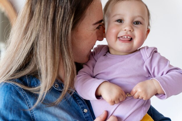 Süßes Baby, das von seiner Mutter gehalten wird und lächelt